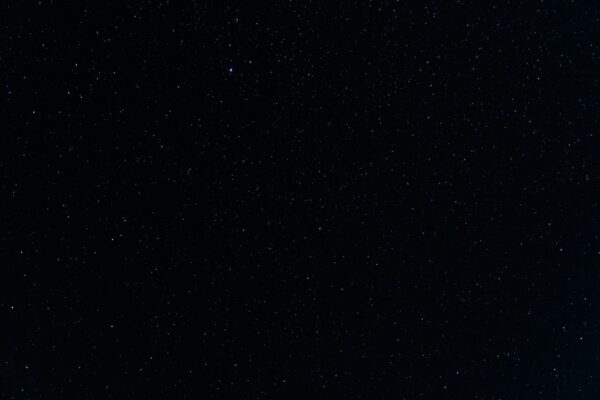 a night sky with stars and a plane in the foreground