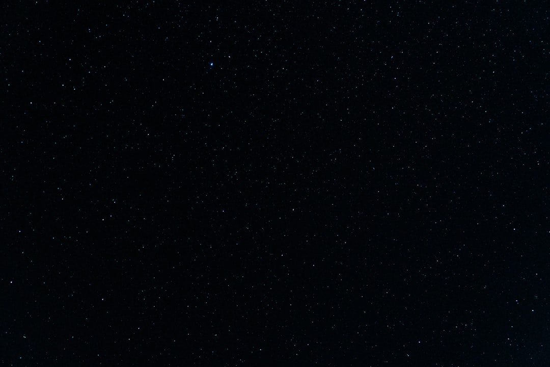 a night sky with stars and a plane in the foreground