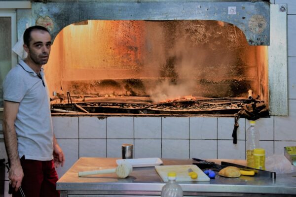 Man standing in a kitchen with a large wood-fired oven