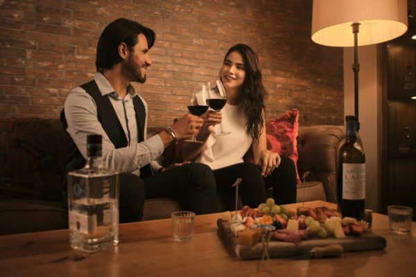 a man and a woman sitting on a couch holding wine glasses