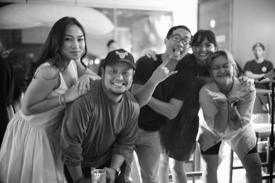 A group of five people posing together in a black and white indoor setting
